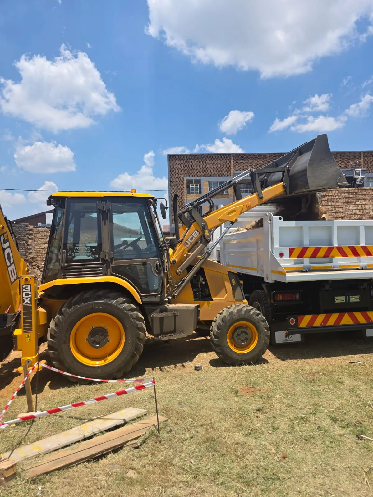 A TLB loading a tipper truck on site